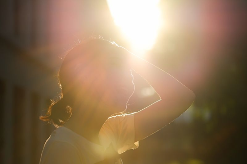 Silhouette di una donna di fronte a un clima caldo con bagliore del sole a causa dei cambiamenti climatici