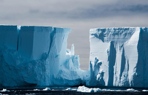 Bianco iceberg galleggiante a forma di tavola nel Mar di Weddell al largo della costa dell'Antartide con un cielo grigio cupo