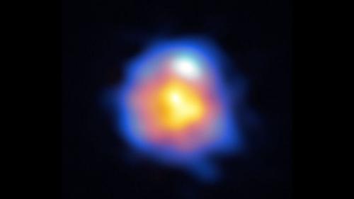 L'emissione a onde submillimetriche dalla superficie stellare è mostrata in arancione, mentre le emissioni del maser di cianuro di idrogeno a 891 GHz sono mostrate in blu. Le osservazioni mostrano che una struttura gassosa a forma di anello circonda la stella e che il gas dalla stella sta sfuggendo allo spazio circostante.