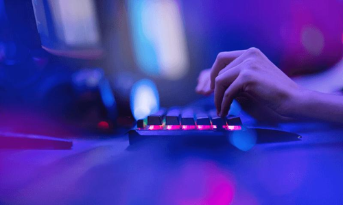 L'hacker usa la tastiera, scuote i pulsanti con le dita per violare la password. Concetto di sicurezza informatica, attacco informatico. Colore blu neon.
