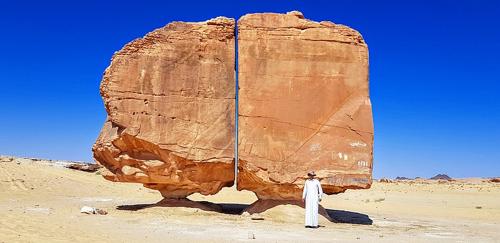 Roccia di Al Naslaa con un uomo in piedi davanti