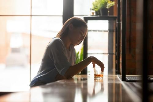 Donna seduta da sola al bar con un drink in mano