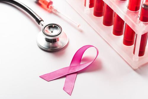 nastro rosa per la consapevolezza del cancro al seno accanto a uno stetoscopio e a un supporto di provette contenenti liquido rosso