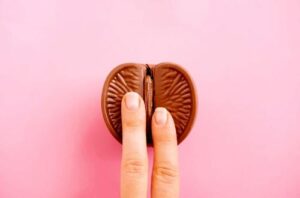 due dita su un'arancia al cioccolato tagliata a metà, su uno sfondo rosa