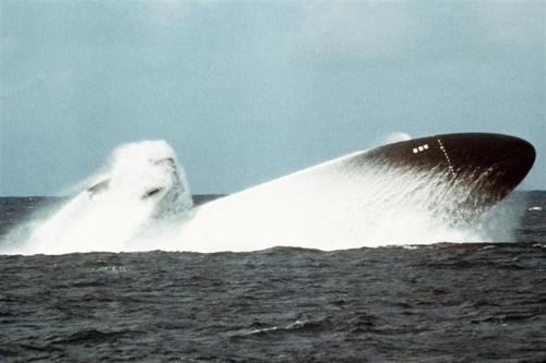 Una foto scattata nel 1978 mostra la prua di un sottomarino nucleare statunitense che emerge dall'acqua come parte di un test. La nave è nera e c'è una nuvola di spruzzi che segue la sua violenta eruzione in superficie.