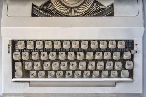 I tasti su una macchina da scrivere bianca disposti nel tradizionale formato QWERTY.