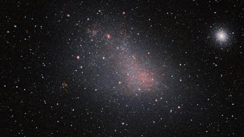 La SMC è una grande collezione nuvolosa di stelle. Oltre alla SMC stessa, questa immagine a campo molto ampio rivela molte galassie di sfondo e diversi ammassi stellari, tra cui il brillante ammasso globulare 47 Tucanae a destra dell'immagine.