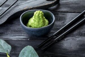 pasta di wasabi verde in una piccola ciotola di ceramica grigia. sfondo di legno nero.