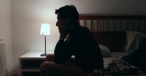 Un uomo si siede a letto alle 3 del mattino dopo essersi svegliato.