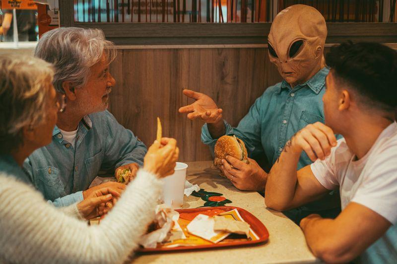 alien che mangia un pasto con gli umani