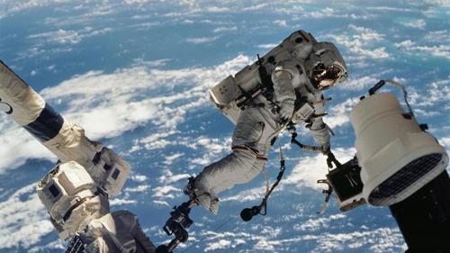 L'immagine mostra l'astronauta che fluttua sopra la Terra con una parte della ISS in fase di installazione