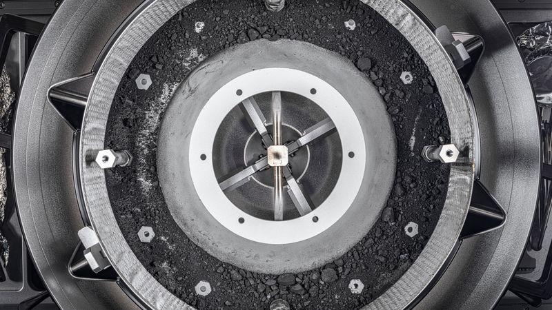 Una vista dall'alto del meccanismo di acquisizione del campione OSIRIS-REx Touch-and-Go-Sample-Acquisition-Mechanism (TAGSAM) con il coperchio rimosso, rivelando il resto del campione di asteroide all'interno.