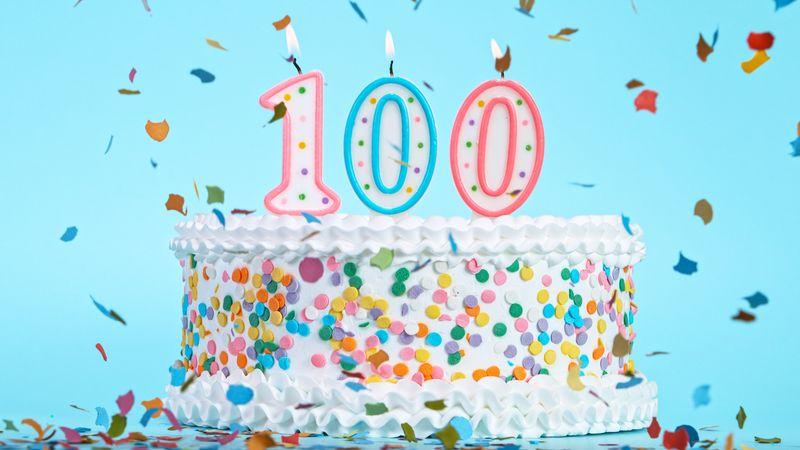 Torta di compleanno colorata con candeline a forma del numero 100.
