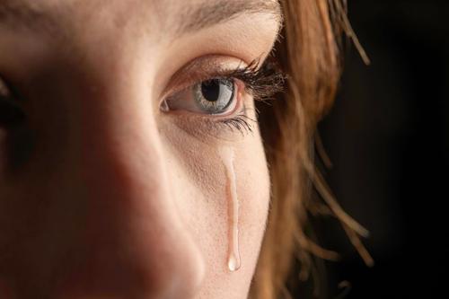 foto ravvicinata di una giovane donna che piange con una lacrima che scende sulla sua guancia.