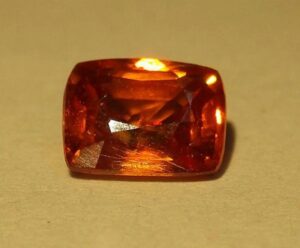Sample of kyawthuite, orange gemstone on yellow background