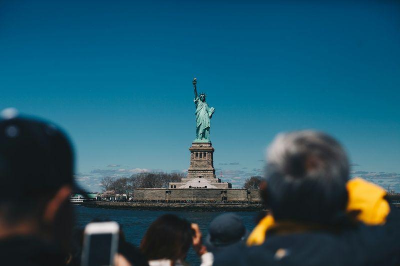 Una folla di turisti scatta fotografie al Monumento Nazionale della Statua della Libertà, New York, Stati Uniti