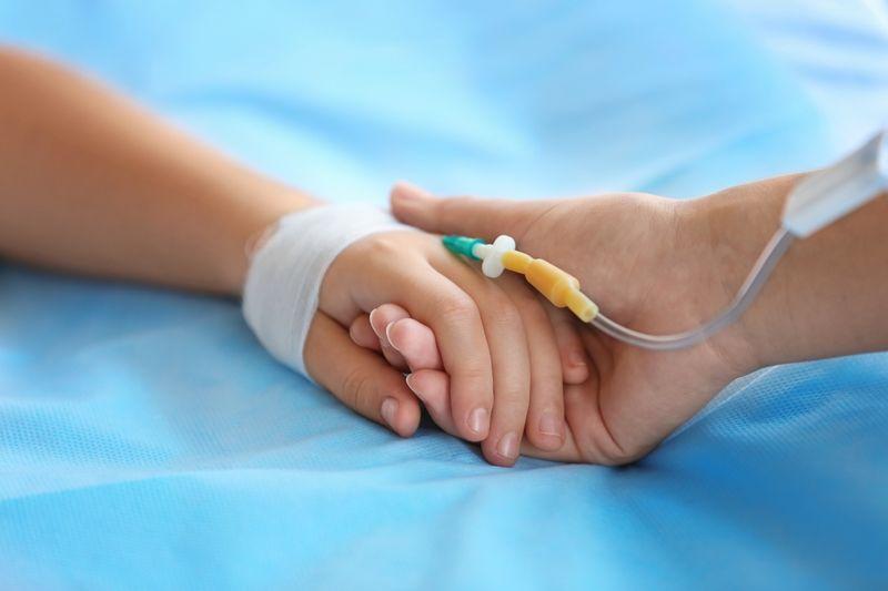 parent holding a child's hand in hospital