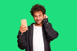 Uomo che tiene in mano il telefono e si copre l'orecchio