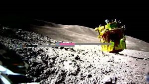 una foto della superficie della luna e il lander è visto di lato con parte del razzo puntato verso l'alto e i pannelli solari rivolti verso gli osservatori