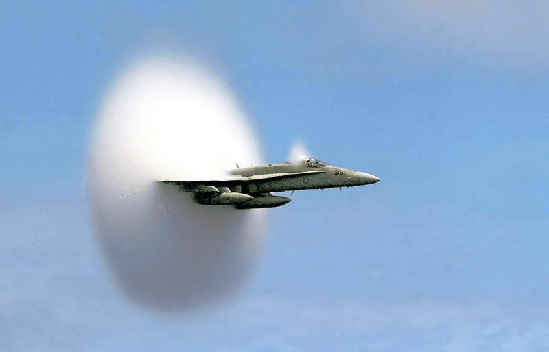Un F/A-18 Hornet rompe il muro del suono nei cieli sopra l'Oceano Pacifico, producendo condensazione localizzata