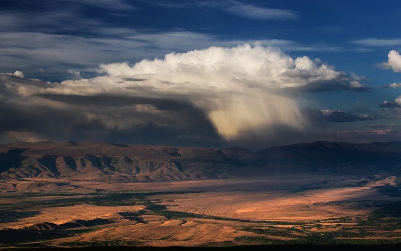 A top view to sunset highland yellow steppe plateau valley on a background of dramatic mountains ridges ranges under dawn white rain virga clouds and blue sky, Kurai, Altai Mountains, Siberia, Russia