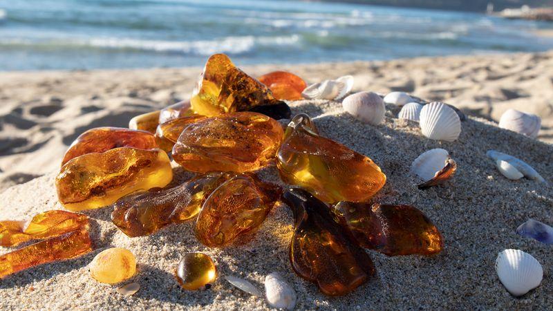 Lucidi e trasparenti pietre d'ambra baltica su una spiaggia sabbiosa.