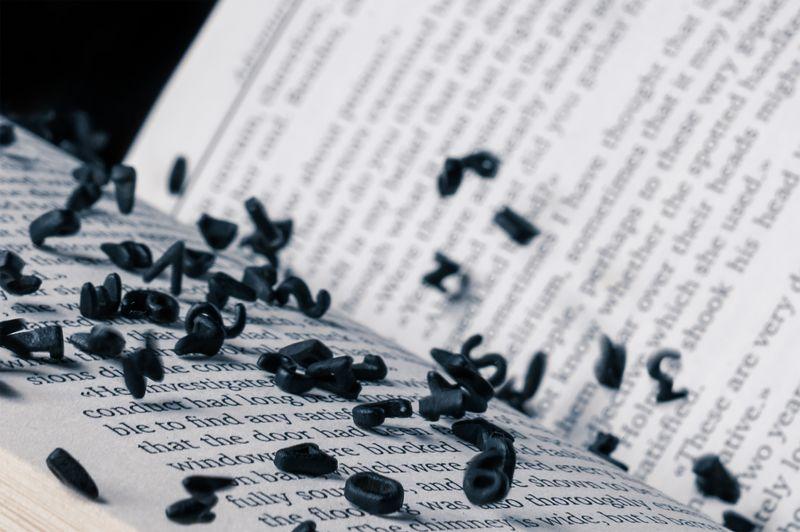 Libro aperto con lettere nere che cadono. Lettere dell'alfabeto in levitazione nell'aria sopra il libro aperto