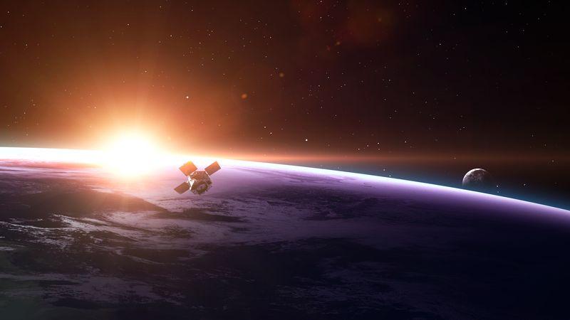 satellite in orbita sopra la Terra con la Luna visibile sullo sfondo e il sole appena sorgente