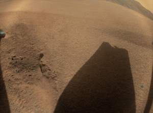 Un'immagine che mostra la sabbia rossa di Amrs e l'ombra approssimativamente rettangolare della pala del rotore. La fine è chiaramente rotta