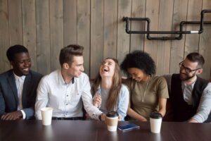 Giovane gruppo di persone che chiacchierano e ridono, seduti in un caffè.