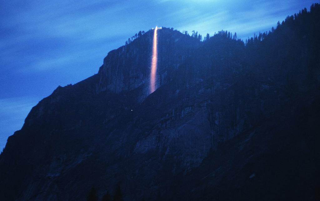 Un unico getto di oro e rosso cade lungo una scogliera altrimenti blu. Fotografia a lunga esposizione