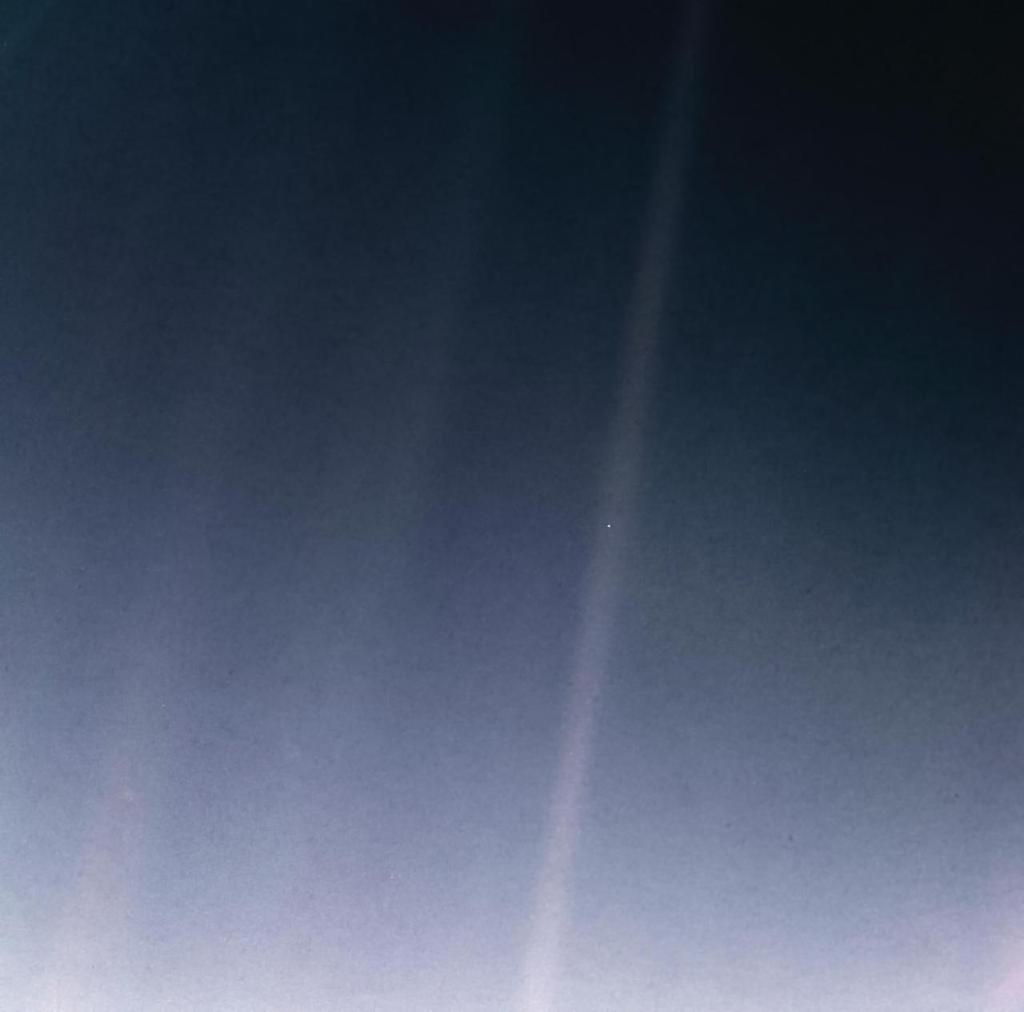 Versione rimasterizzata della fotografia del Punto Blu Pallido scattata dalla missione Voyager nel 1990; il pianeta Terra è visibile come un minuscolo puntino bianco verso il centro dell'immagine altrimenti blu/grigia