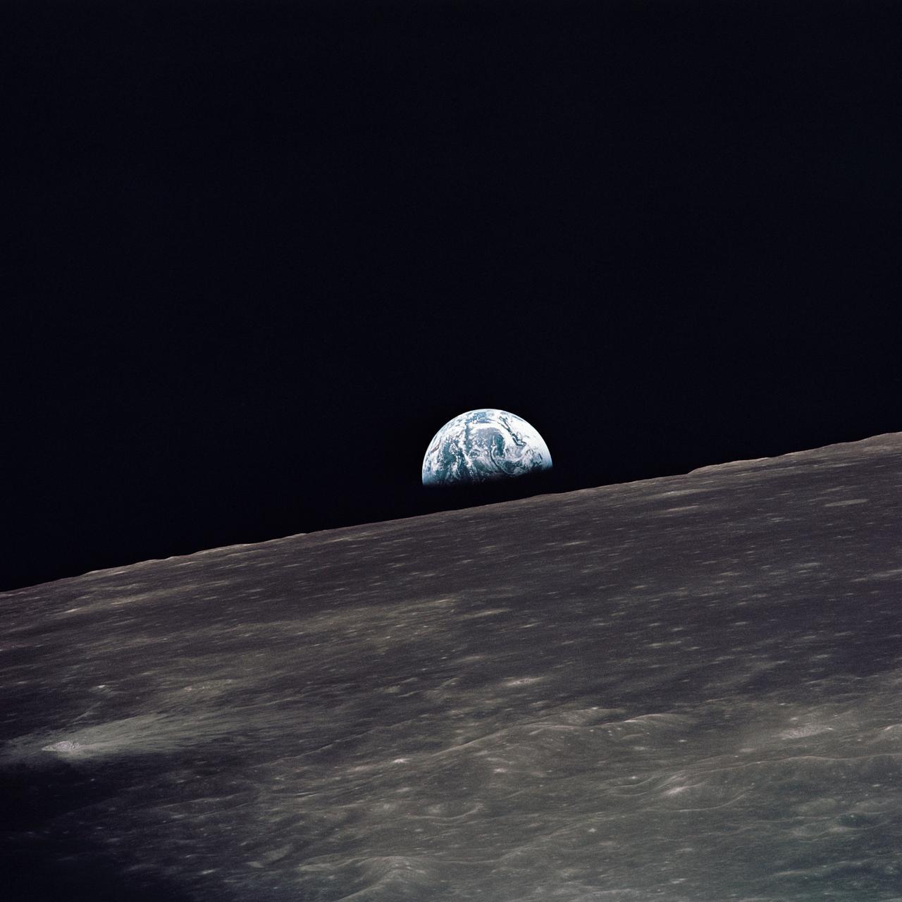 Una vista della Terra che sorge sopra l'orizzonte lunare fotografata dal Modulo Lunare Apollo 10, guardando verso ovest nella direzione del viaggio. Il Modulo Lunare al momento in cui è stata scattata la foto si trovava sopra le alte terre del lato lontano della Luna a circa 105 gradi di longitudine est.