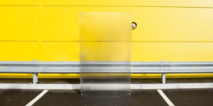 Un uomo che sporge la testa dietro uno scudo di invisibilità di fronte a un muro giallo.