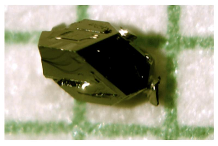 un cristallo verde scuro è visto su una carta reticolata