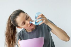 Irrigazione nasale. Una giovane ragazza usa il Neti Pot per trattare il suo naso che cola e i raffreddori.