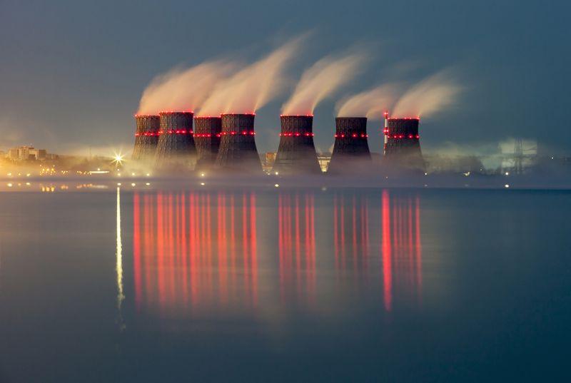 Le torri di raffreddamento delle centrali nucleari emettono vapore di fronte a un riflesso del fiume.