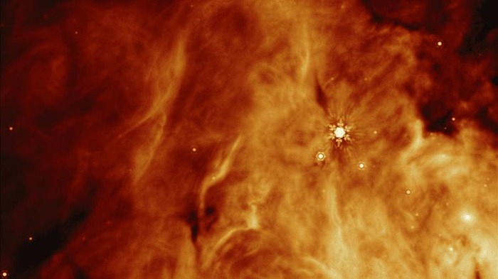 Una nuvola arancione è visibile con un pugno di oggetti stellari che appaiono al suo interno.