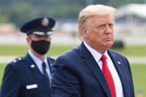 Una foto di Donald Trump durante la sua presidenza. Sta in piedi di fronte a un generale dell'Aeronautica indossando una mascherina nera durante la pandemia.