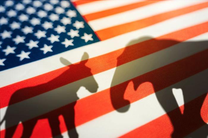 Bandiera americana con le ombre di un asino e un elefante sovrapposti; l'asino rappresenta il partito democratico e l'elefante il partito repubblicano.