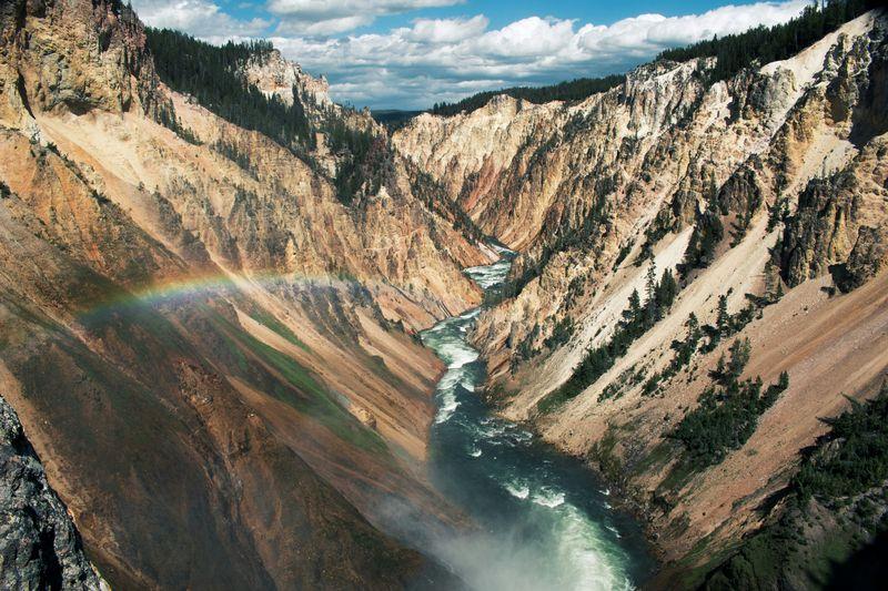 Un arcobaleno attraverso una valle montana e un fiume nel Parco Nazionale di Yellowstone.