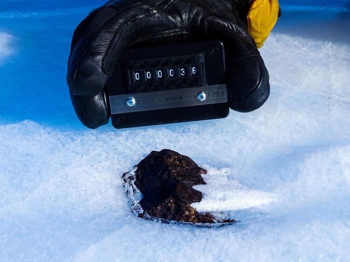 Meteorite antartico (HUT 18036) parzialmente nel ghiaccio, in contrasto con la maggior parte dei campioni che vengono raccolti mentre giacciono in superficie. 