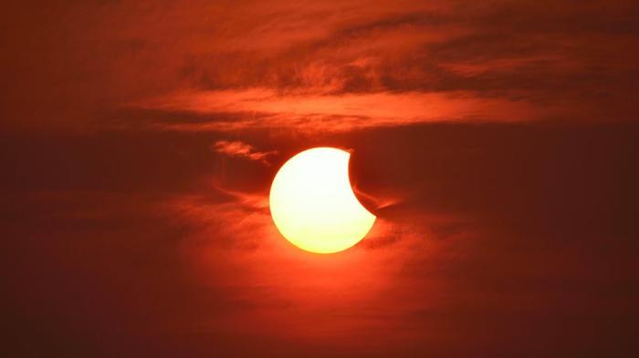 Un'eclissi solare parziale che avviene con molte nuvole nel cielo