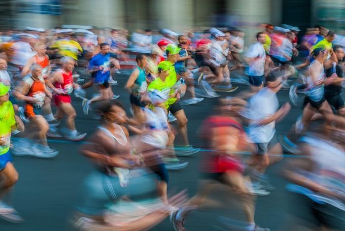 Un'immagine sfocata di corridori di maratona su una strada cittadina. 