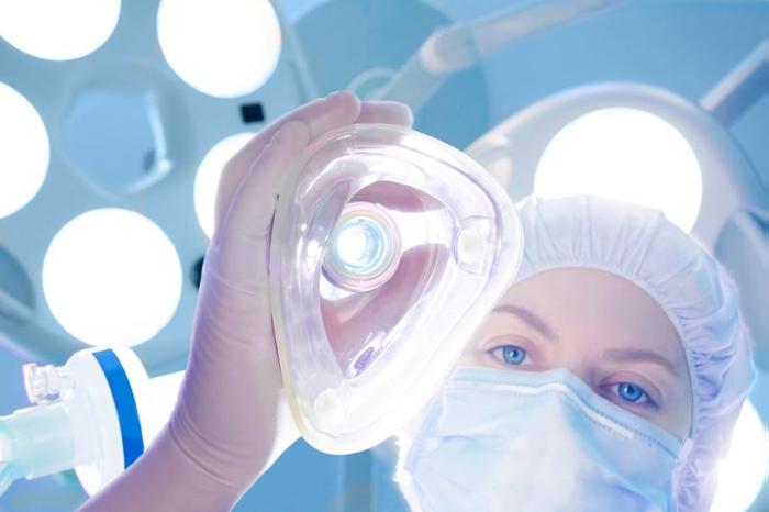 person-in-surgical-cap-and-mask-lowering-a-surgical-gas-mask-down-towards-the-camera-m-1-1.jpg