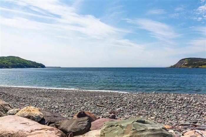 rocky-beach-with-blue-sky-and-green-land-masses-in-the-background-m-1.jpg