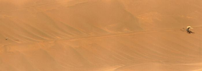 NASA s Ingenuity Mars Helicopter, right, stands near the apex of a sand ripple. A fragment of its rotor is far to the left of the image
