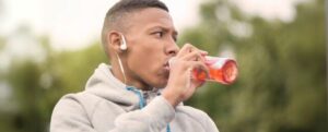 Uomo all'aperto con felpa che beve una bevanda rossa