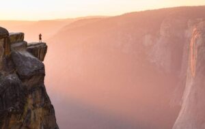 Un escursionista si trova sul bordo di una scogliera a Taft Point che sovrasta El Capitan nel Parco Nazionale di Yosemite tra le montagne Sierra Nevada della California.