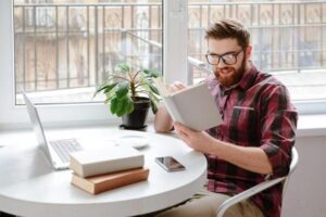 Giovane Uomo che Legge un Libro al Tavolo